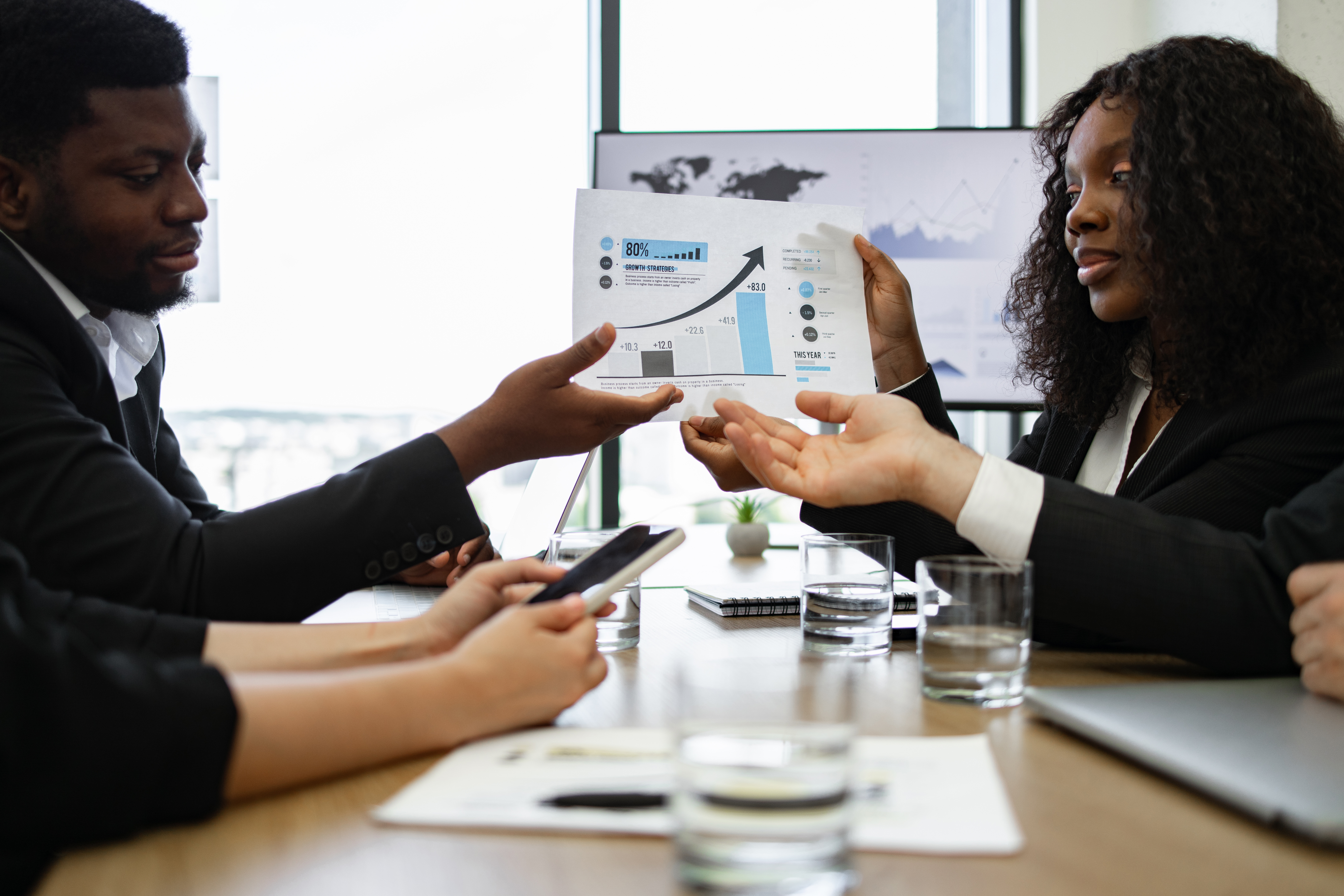 Business colleagues discussing financial report in office meeting Business colleagues in formal attire discussing financial report during meeting. Collaboration, analysis, teamwork, and communication concept in modern office environment.